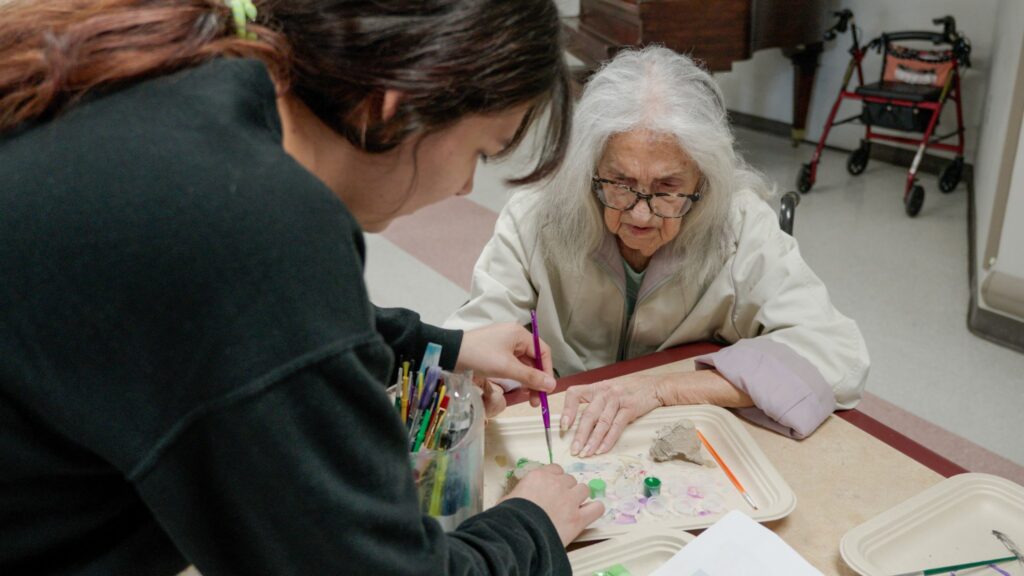 A woman and nurse painting as a memory care tool at Care Manor
